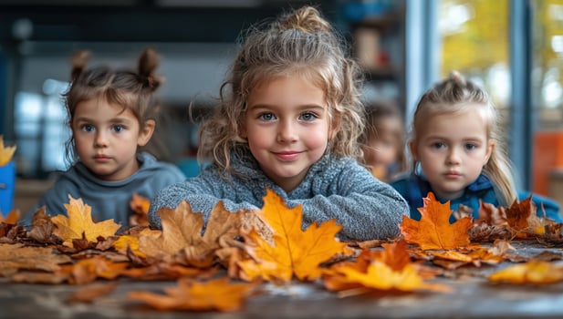 Three children at wooden table with autumn leaves enjoying seasonal activities photo