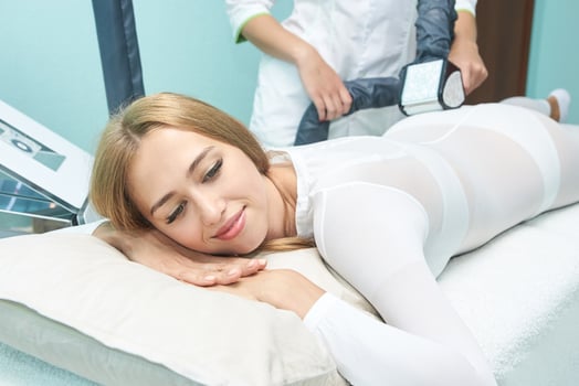 Caucasian female receiving body contouring treatment with relaxed expression in spa setting. photo