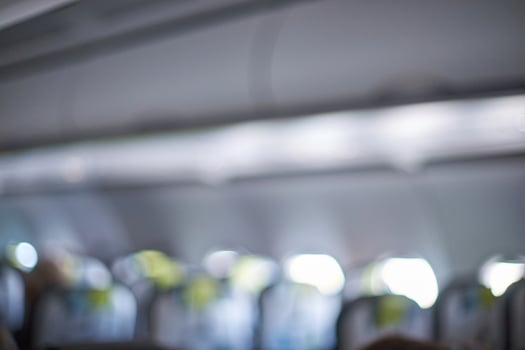 Blurry interior of airplane cabin with rows of seats and overhead compartments in soft focus. photo