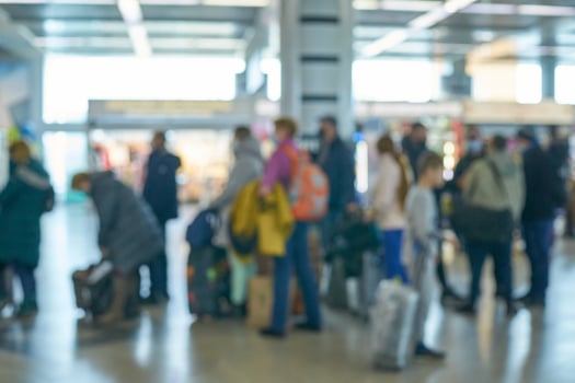 Blurred crowd of travelers at busy airport terminal with luggage and backpacks. photo