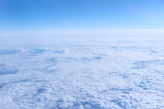Expansive aerial view of white fluffy clouds with blue sky background in daylight. photo