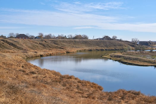 Serene riverbend in autumn landscape with clear blue sky and distant rural homes. photo