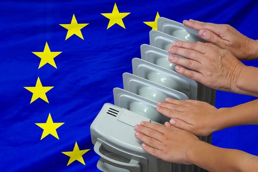 Hands of woman and teen near a hot home radiator on European Union flag background photo
