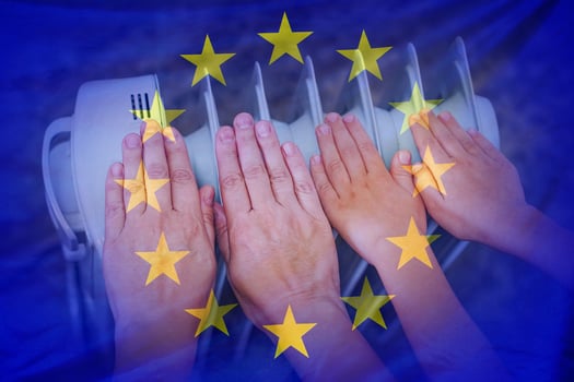 Hands of woman and teen near a hot home radiator on flag EU background photo
