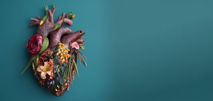 Realistic heart sculpture adorned with vibrant flowers, symbolizing life and nature. photo
