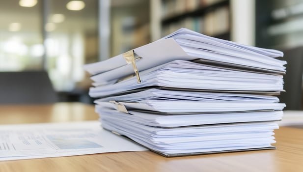 Office paperwork stack, desk, documents, blurred background, business photo