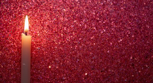 Candlelight Glow. A Warm Flame Against a Shimmering Red Background, Illuminating the Scene photo