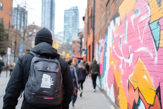 Person walking on urban street with colorful mural on brick wall photo