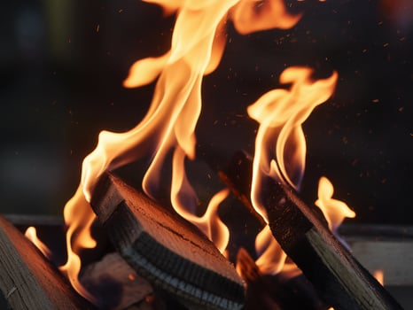 Close-up of vibrant orange flames dancing above charred wooden logs. photo