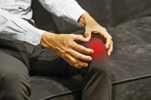 Elderly man with his hands on a painful knee joint at home photo