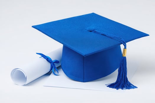A blue graduation cap rests next to a rolled diploma tied with a ribbon. This symbolizes educational success and the joy of completing a degree. Perfect for celebrating achievements. photo