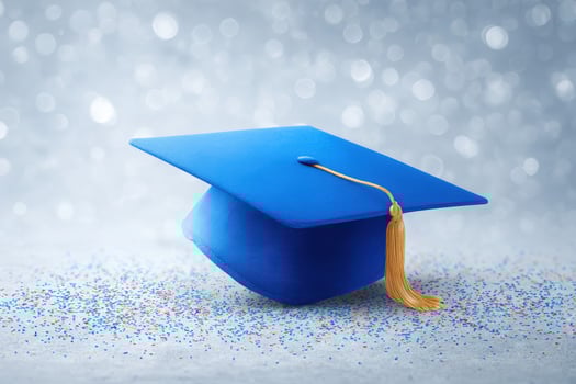 A blue graduation cap rests on a surface scattered with colorful confetti, set against a glimmering silver backdrop. The atmosphere feels festive and marks an achievement. photo
