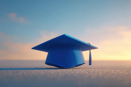A blue graduation cap sits on a flat surface against a stunning sunset backdrop. The vibrant colors of the sky create a sense of hope and new beginnings. photo