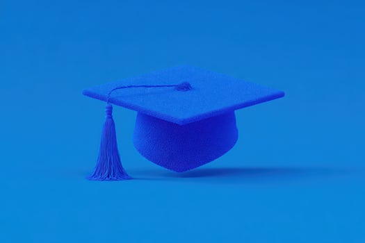 A vibrant blue graduation cap with a long tassel is prominently displayed against a solid blue background. The cap symbolizes achievement and celebration in academic life. photo