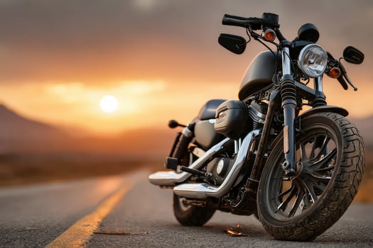 A motorcycle stands prominently on a winding road as the sun sets in the background, casting an orange glow over the landscape. The bikes sleek design contrasts with the natural scenery. photo