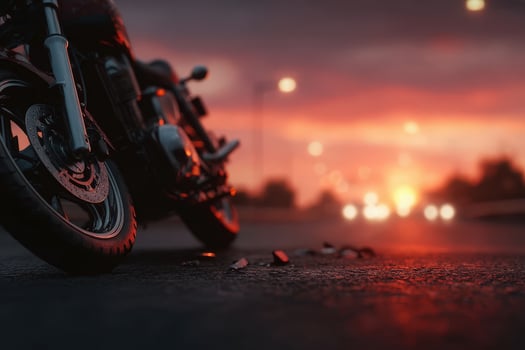A motorcycle stands on the highway, illuminated by the warm glow of the sunset. The scene captures the serene ambiance with blurred vehicles in the background, highlighting the beauty of dusk. photo