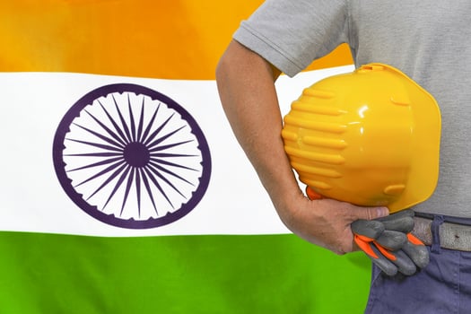 Hand of worker and yellow hard-hat on background flag India photo