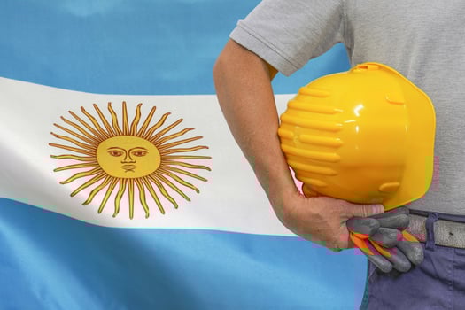 Hand of worker and yellow hard-hat on background flag Argentina photo