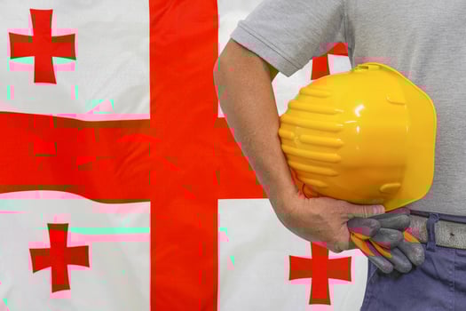 Hand of worker and yellow hard-hat on background flag Georgia photo