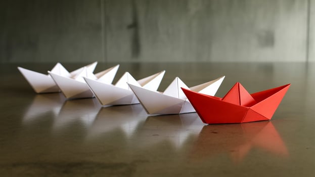 Red origami paper boat leads a line of white origami paper boats leadership innovation photo