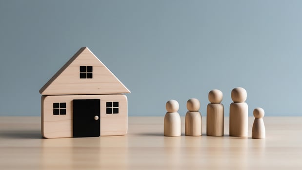 Wooden house and family figures arranged on a table against a light blue wall home photo