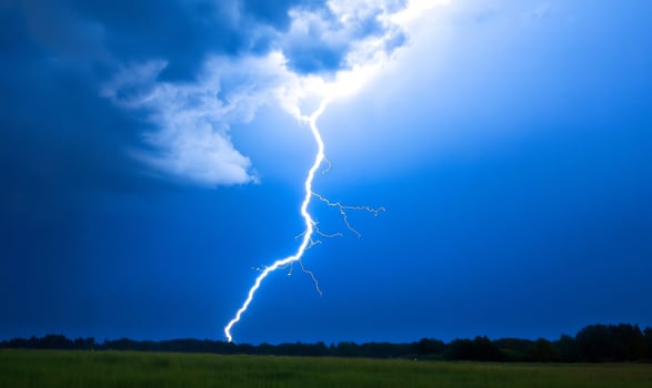 Lightning strike over field at night photo