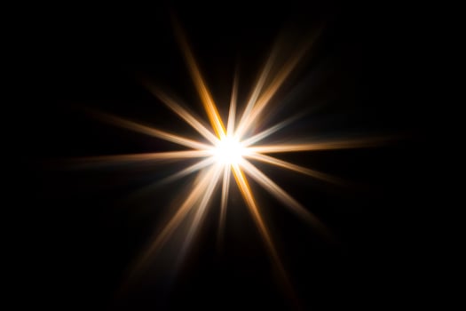 Golden starburst light effect, black background, design element photo