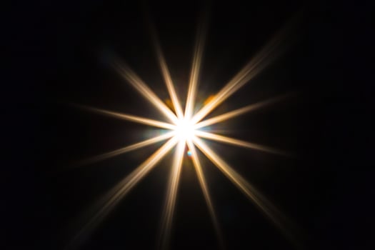 Bright starburst light flare, dark background, design element photo