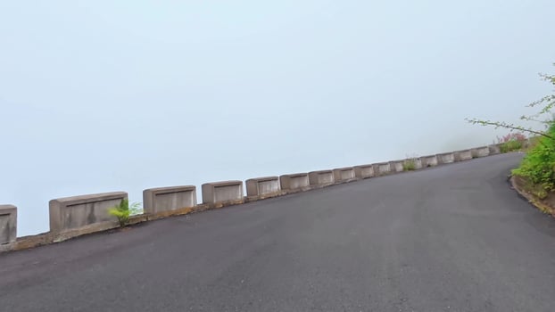 A road with a fence on the side and a hill in the background photo