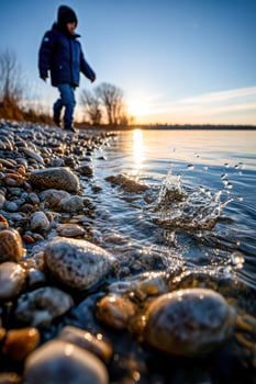 Child walks on pebble beach at sunset photo