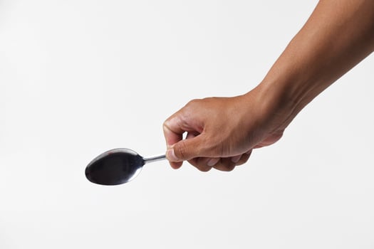 Close-up of male hand scooping with iron spoon isolated on white photo