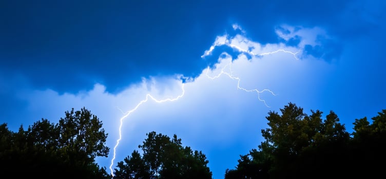 Lightning strike over trees, night sky, weather photo