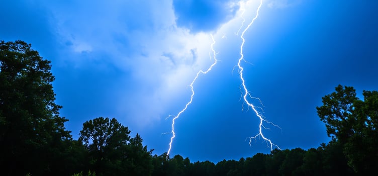 Lightning strike over trees at night photo