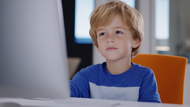 Boy using computer, learning online, home office, bright room photo