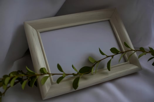 A white frame with green leaves on it photo