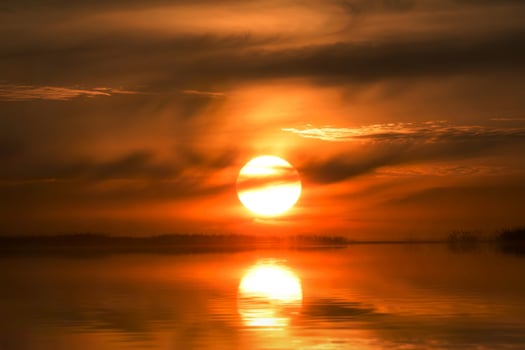 A beautiful sunset over a lake with a large sun photo