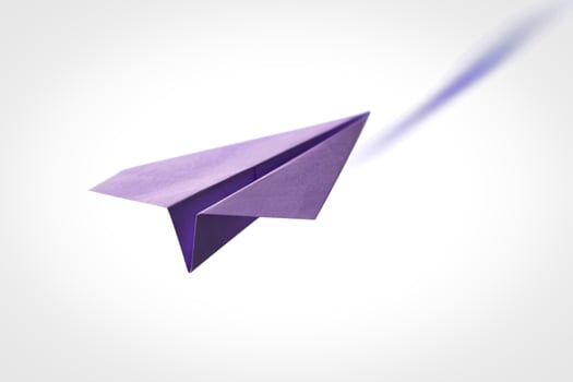 A purple paper airplane flying in the air photo