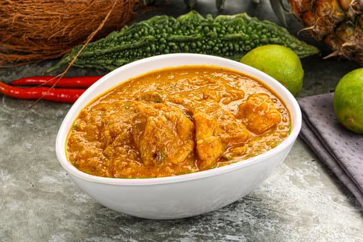 A bowl of curry with a coconut and lime photo