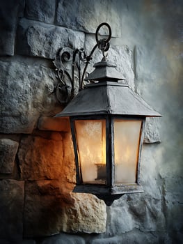 Illuminated Antique Lantern on Rustic Stone Wall. A close up image of a vintage style wall mounted light fixture glowing warmly against a textured stone background. photo