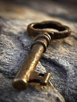 Antique Golden Key Resting on a Rough Stone Surface. A Close Up Image of a Weathered Key. photo