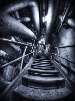 Industrial Staircase Leading Down into a Network of Pipes. A dark, mysterious descent into the depths of a factory or power plant. photo