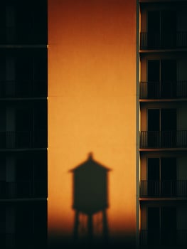 Sunset Shadow of a Water Tower on an Apartment Building Wall. photo