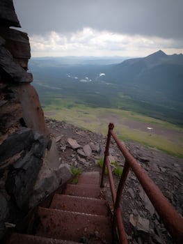 Rusty Metal Stairs Leading to a Mountaintop Vista. A breathtaking panoramic view of a valley unfolds from the summit. photo