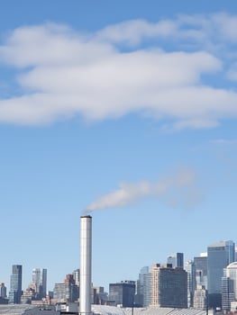 Industrial Chimney with Smoke Against a City Skyline and Blue Sky. photo