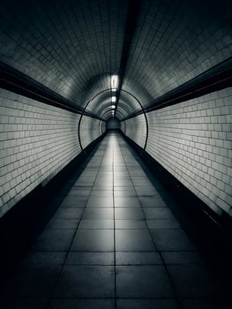 A long, tiled tunnel leading to a bright light at the end. photo
