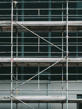 Metal Scaffolding Structure Against a Building Exterior. A close up view of scaffolding against a dark teal building exterior. photo