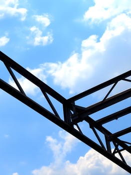 Steel Structure Against a Blue Sky with Clouds. A low angle close up of a metal framework set against a bright blue sky and fluffy white clouds. photo