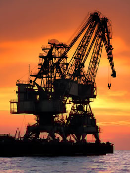 Silhouette of a Large Industrial Crane at Sunset Over Water. photo