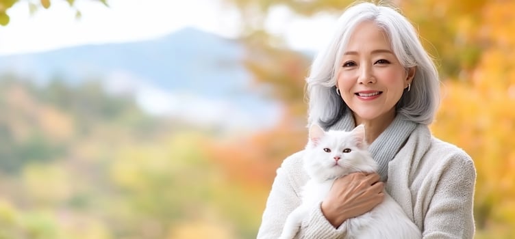 Senior woman holding cat, autumn park photo