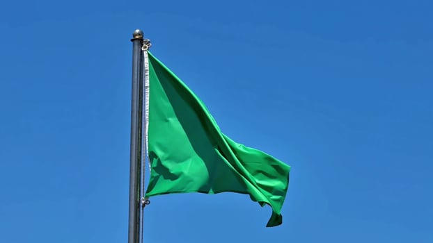A green flag flying in the wind against a blue sky photo
